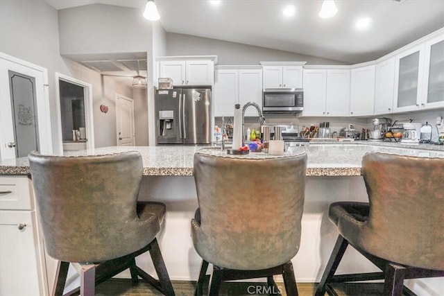 17993 Mondamon Rd, Apple Valley, CA 92307 - kitchen featuring stainless steel appliances, vaulted ceiling, white cabinets, glass insert cabinets, and a kitchen breakfast bar