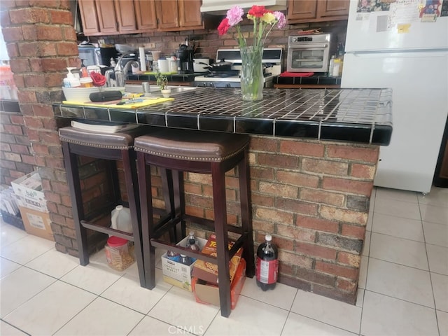 8502 Borson St, Downey, CA 90242 - kitchen with freestanding refrigerator, tile countertops, stove, and light tile patterned floors