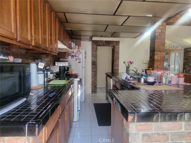8502 Borson St, Downey, CA 90242 - kitchen featuring black microwave, under cabinet range hood, brown cabinets, and light tile patterned floors