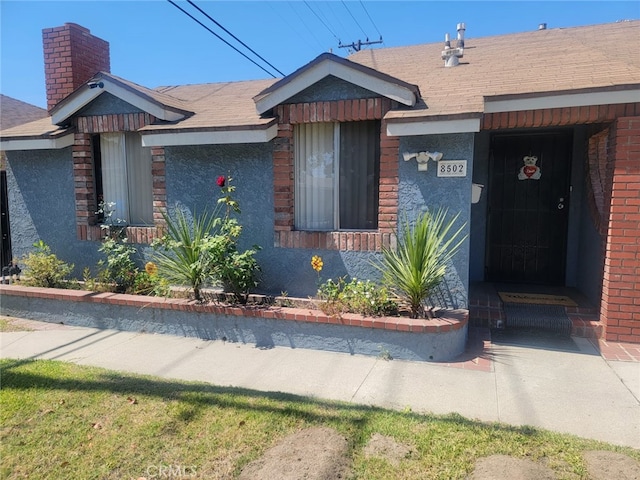 8502 Borson St, Downey, CA 90242 - view of front of home with a chimney, a shingled roof, and brick siding