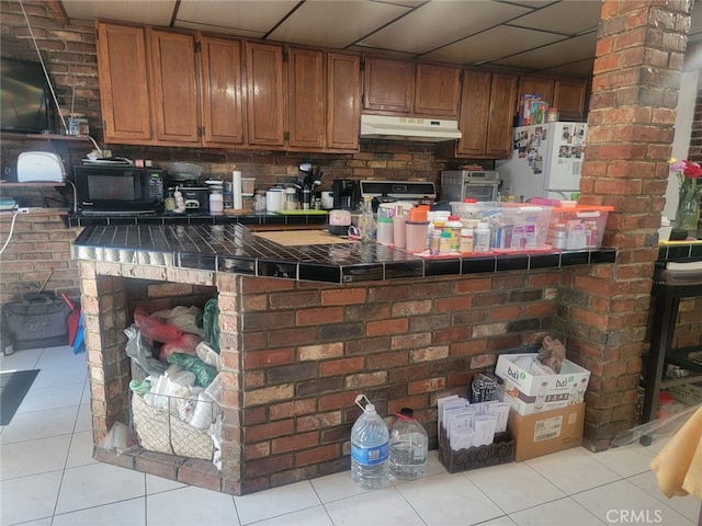8502 Borson St, Downey, CA 90242 - kitchen with tile counters, freestanding refrigerator, under cabinet range hood, black microwave, and light tile patterned flooring