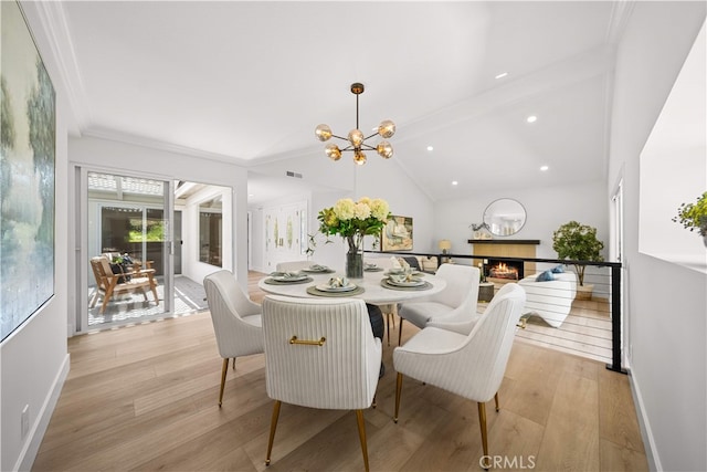 12 Creekside, Irvine, CA 92603 - dining space with light wood-style flooring, a lit fireplace, a chandelier, and crown molding
