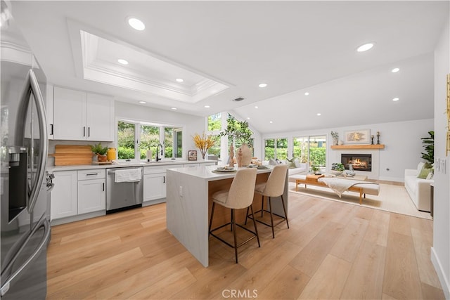 12 Creekside, Irvine, CA 92603 - kitchen featuring appliances with stainless steel finishes, open floor plan, a kitchen island, a breakfast bar, and plenty of natural light