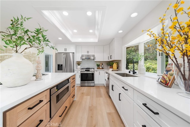 12 Creekside, Irvine, CA 92603 - kitchen featuring appliances with stainless steel finishes, a raised ceiling, light wood-type flooring, tasteful backsplash, and recessed lighting