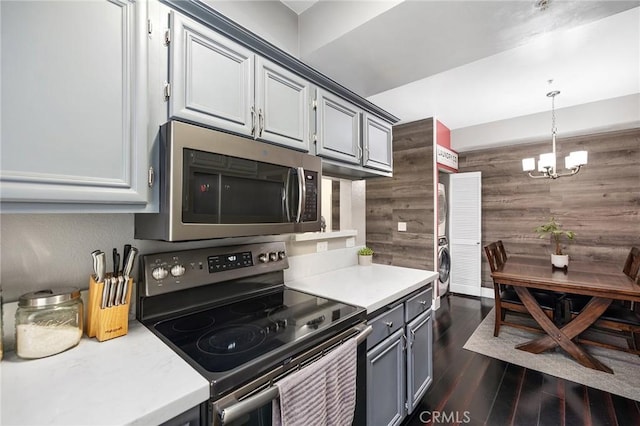 375 Central Ave Unit 196, Riverside, CA 92507 - kitchen with stainless steel appliances, stacked washer and clothes dryer, light countertops, a chandelier, and wood walls