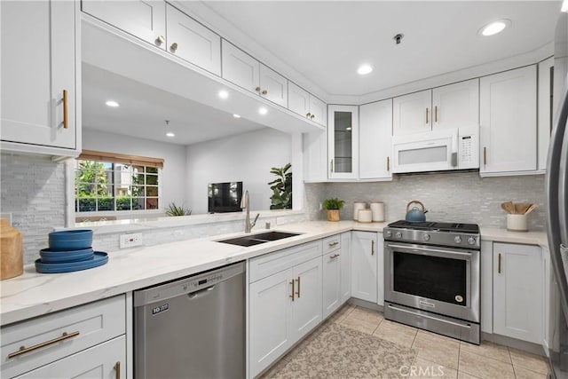 409 Utica Ave Unit C23, Huntington Beach, CA 92648 - kitchen with stainless steel appliances, white cabinetry, decorative backsplash, light tile patterned floors, and recessed lighting