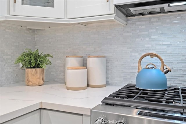 409 Utica Ave Unit C23, Huntington Beach, CA 92648 - kitchen view of backsplash, exhaust hood, white cabinets, stove, and light stone counters