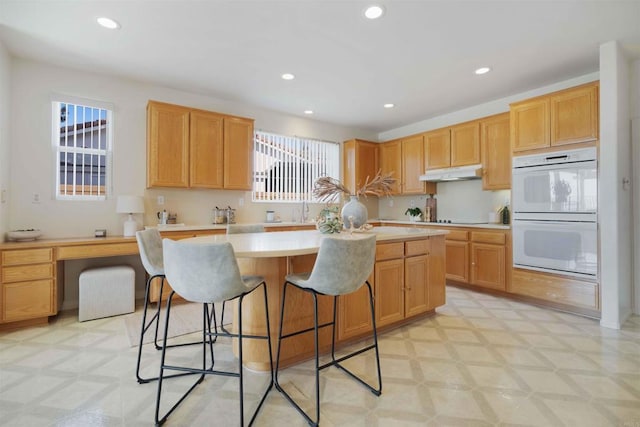 837 Calle Lagasca, Chula Vista, CA 91910 - kitchen featuring white double oven, light flooring, under cabinet range hood, a center island, and recessed lighting