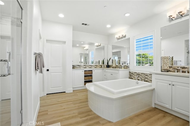 12 Rastro St, Rancho Mission Viejo, CA 92694 - bathroom with a stall shower, two vanities, a bath, wood finished floors, and recessed lighting
