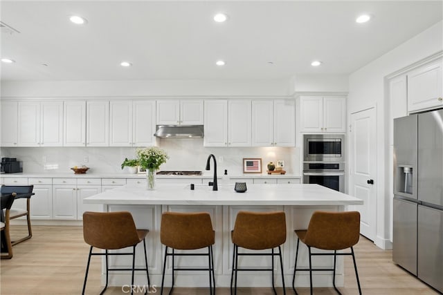 12 Rastro St, Rancho Mission Viejo, CA 92694 - kitchen with appliances with stainless steel finishes, under cabinet range hood, white cabinetry, tasteful backsplash, and recessed lighting