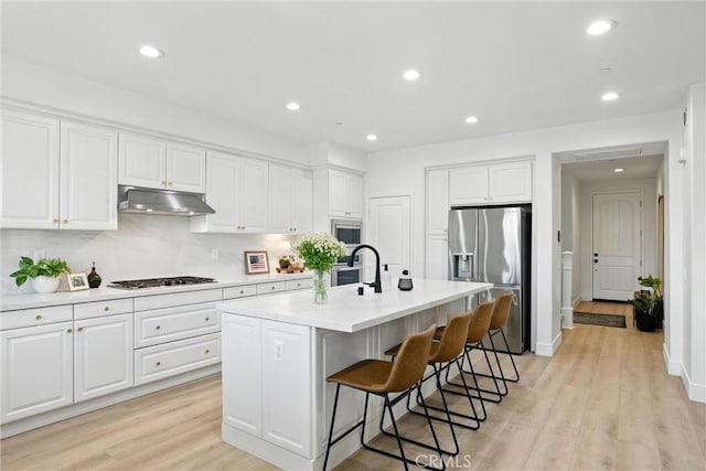 12 Rastro St, Rancho Mission Viejo, CA 92694 - kitchen featuring appliances with stainless steel finishes, under cabinet range hood, white cabinets, a breakfast bar area, and light countertops