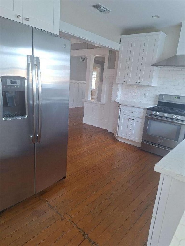 2109 N Marengo Ave, Altadena, CA 91001 - kitchen featuring appliances with stainless steel finishes, wall chimney exhaust hood, dark wood-style floors, white cabinets, and backsplash