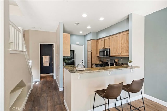 23612 Muir Trl Unit 74, Valencia, CA 91354 - kitchen featuring stainless steel microwave, range, dark wood finished floors, freestanding refrigerator, and a kitchen breakfast bar