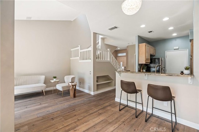 23612 Muir Trl Unit 74, Valencia, CA 91354 - kitchen with wood finished floors, a breakfast bar, recessed lighting, freestanding refrigerator, and light brown cabinets