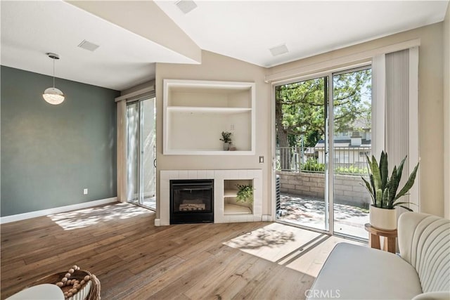 23612 Muir Trl Unit 74, Valencia, CA 91354 - living area with hardwood / wood-style floors, healthy amount of natural light, vaulted ceiling, a tiled fireplace, and built in features