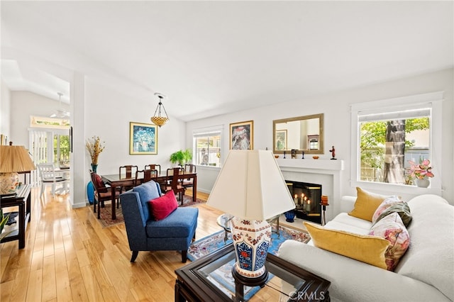 23974 Via Astuto, Murrieta, CA 92562 - living room featuring plenty of natural light, light wood-style floors, a glass covered fireplace, and lofted ceiling