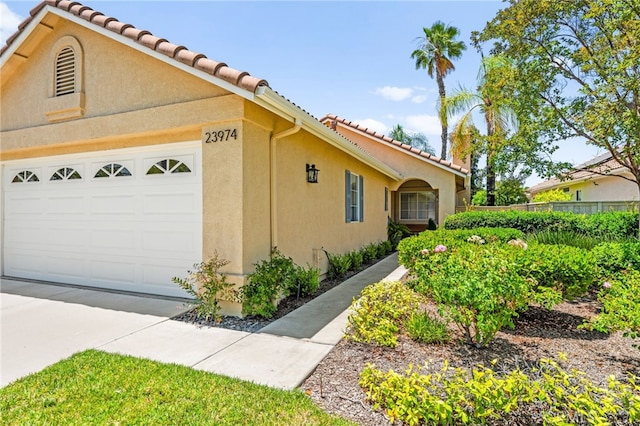 23974 Via Astuto, Murrieta, CA 92562 - view of home's exterior with a garage, stucco siding, a tiled roof, and driveway