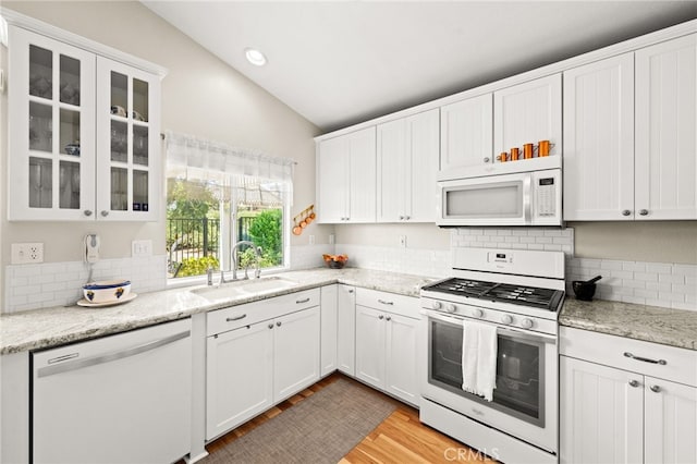 23974 Via Astuto, Murrieta, CA 92562 - kitchen with white appliances, vaulted ceiling, backsplash, white cabinetry, and light wood-style flooring
