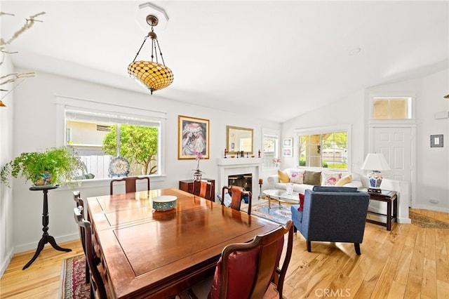 23974 Via Astuto, Murrieta, CA 92562 - dining room with light wood-style floors, healthy amount of natural light, lofted ceiling, and a glass covered fireplace