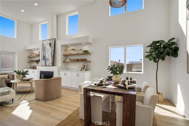 16743 Bayview Dr Unit A, Sunset Beach, CA 90742 - living room featuring a towering ceiling, light wood-style floors, recessed lighting, and a glass covered fireplace