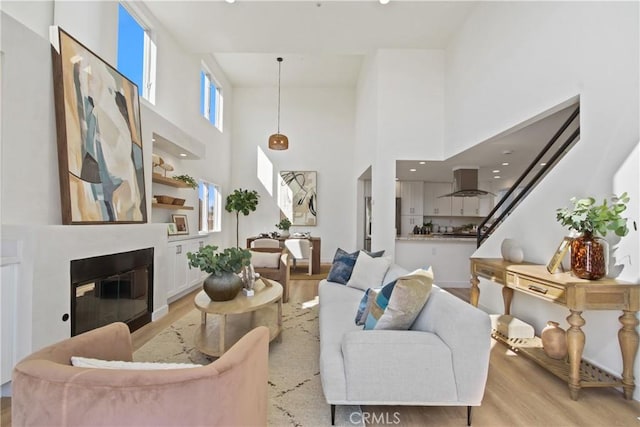 16743 Bayview Dr Unit A, Sunset Beach, CA 90742 - living area featuring a towering ceiling, light wood finished floors, and a glass covered fireplace