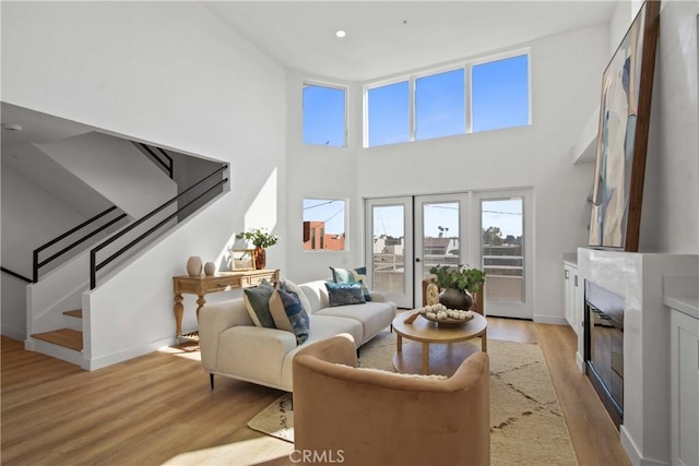 16743 Bayview Dr Unit A, Sunset Beach, CA 90742 - living room with light wood-type flooring, a glass covered fireplace, stairs, a high ceiling, and recessed lighting