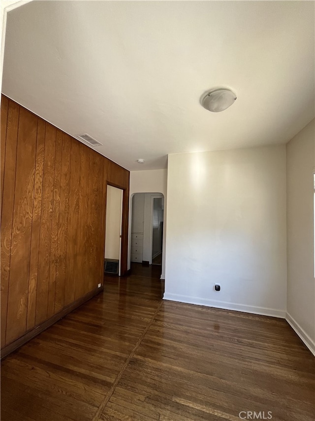 10563 Las Lunitas Ave, Tujunga, CA 91042 - unfurnished room with dark wood-style flooring, wooden walls, and arched walkways