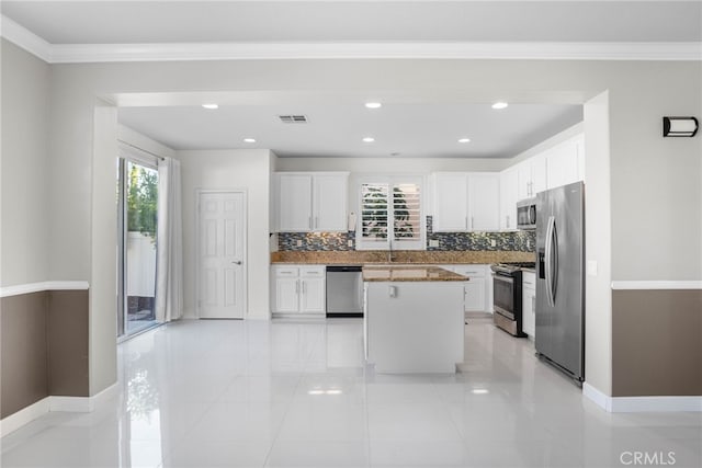 23825 Lancer Ct, Wildomar, CA 92595 - kitchen with appliances with stainless steel finishes, decorative backsplash, a kitchen island, white cabinetry, and crown molding