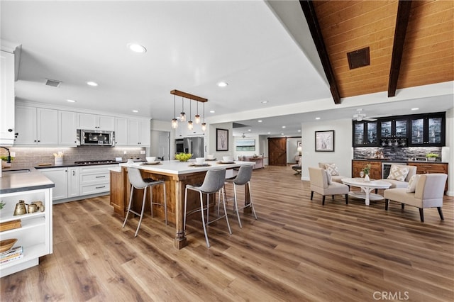 2777 Shadow Canyon Cir, Norco, CA 92860 - kitchen with open floor plan, stainless steel microwave, white cabinetry, decorative backsplash, and a breakfast bar