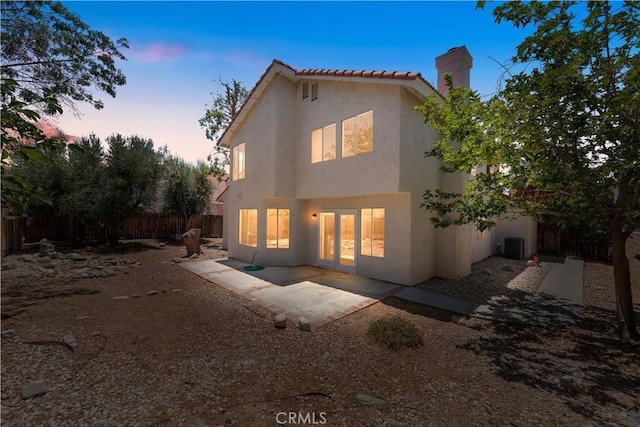 39524 Hawthorne St, Palmdale, CA 93551 - back of house at dusk with stucco siding, a fenced backyard, a chimney, a patio area, and a tile roof