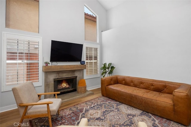 7 Via Olorosa, Rancho Santa Margarita, CA 92688 - living room featuring wood finished floors, a lit fireplace, and a high ceiling