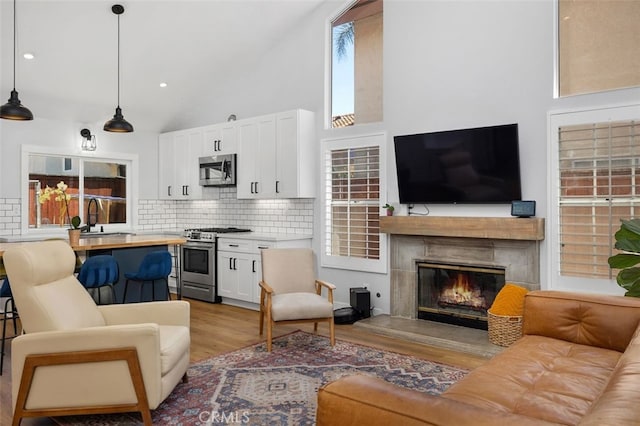 7 Via Olorosa, Rancho Santa Margarita, CA 92688 - living area featuring wood finished floors, a glass covered fireplace, recessed lighting, and high vaulted ceiling