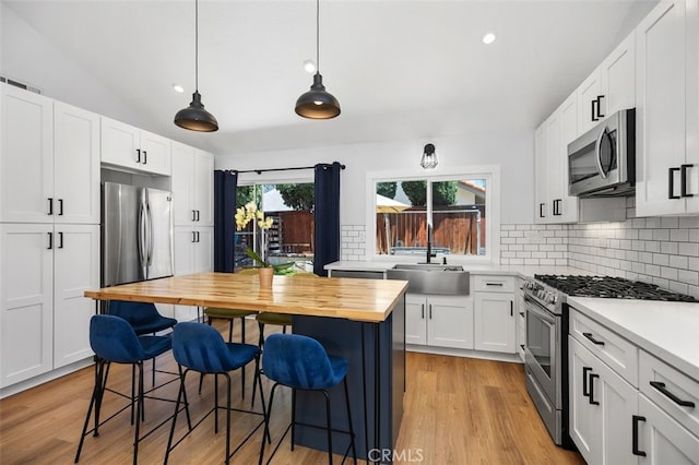 7 Via Olorosa, Rancho Santa Margarita, CA 92688 - kitchen featuring stainless steel appliances, wooden counters, a kitchen breakfast bar, tasteful backsplash, and white cabinetry