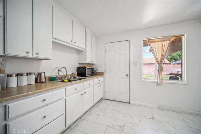 43926 3rd St E, Lancaster, CA 93535 - kitchen featuring light marble finish flooring, stainless steel microwave, white cabinets, and light countertops