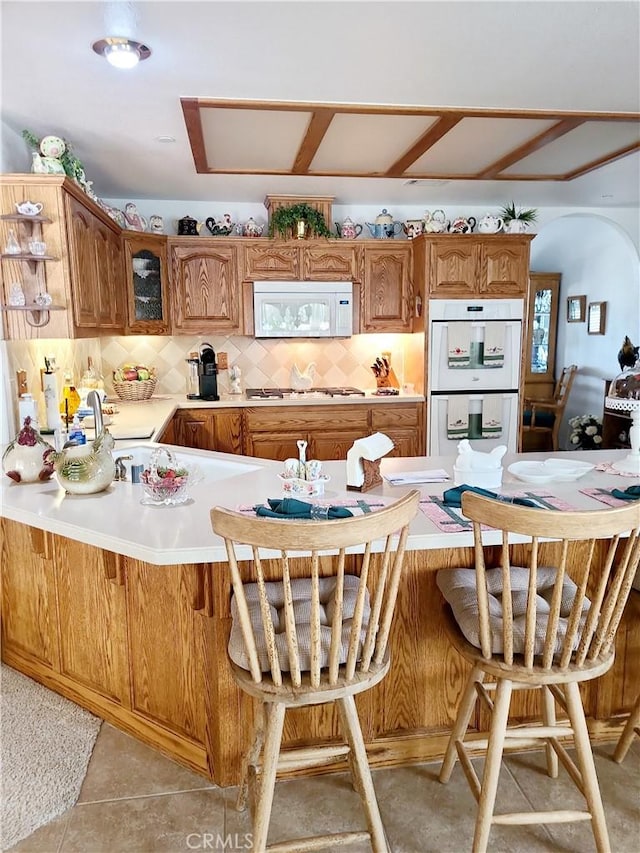 325 Canyon Rd, Pinon Hills, CA 92372 - kitchen with white appliances, a peninsula, light countertops, decorative backsplash, and glass insert cabinets