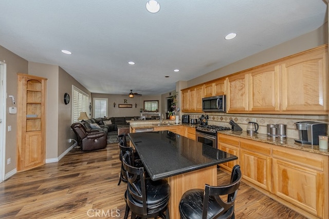 20770 Stony Brook Cir, Riverside, CA 92508 - kitchen featuring appliances with stainless steel finishes, open floor plan, wood finished floors, recessed lighting, and a breakfast bar area