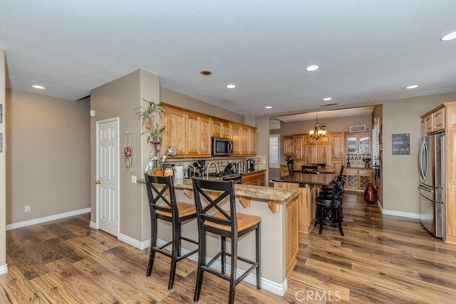 20770 Stony Brook Cir, Riverside, CA 92508 - kitchen with stainless steel appliances, a breakfast bar, wood finished floors, a peninsula, and recessed lighting