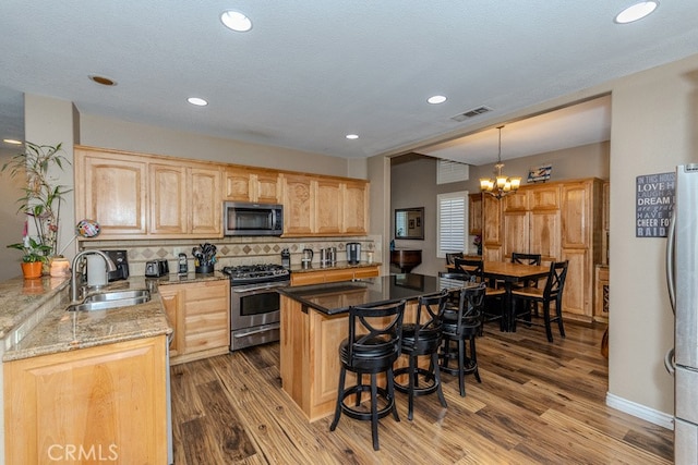 20770 Stony Brook Cir, Riverside, CA 92508 - kitchen featuring appliances with stainless steel finishes, a breakfast bar, light brown cabinets, light stone counters, and a chandelier