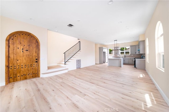 2709 Cogswell Rd Unit B, El Monte, CA 91732 - unfurnished living room with light wood finished floors, stairway, and arched walkways