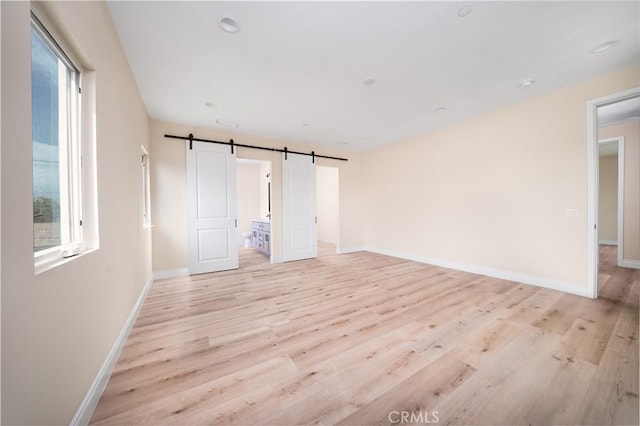 2709 Cogswell Rd Unit B, El Monte, CA 91732 - unfurnished bedroom featuring multiple windows, light wood-style floors, a barn door, and ensuite bathroom