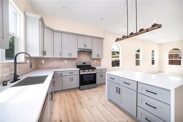 2709 Cogswell Rd Unit B, El Monte, CA 91732 - kitchen featuring gray cabinetry, decorative backsplash, stainless steel gas range oven, light wood-type flooring, and light countertops