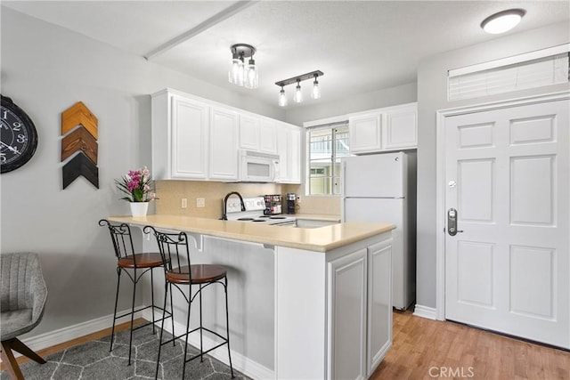 20191 Cape Coral Ln Unit 3-206, Huntington Beach, CA 92646 - kitchen with white appliances, a kitchen breakfast bar, white cabinetry, and light countertops