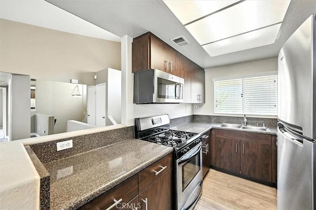 18818 Vista Del Canon Unit G, Newhall, CA 91321 - kitchen featuring stainless steel appliances, dark countertops, light wood-style flooring, and dark brown cabinets