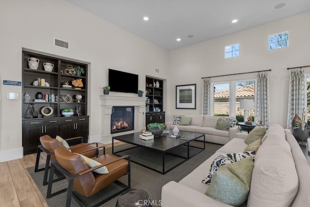 20552 Galloway, Saugus, CA 91350 - living area featuring built in shelves, a high ceiling, light wood-style flooring, recessed lighting, and a glass covered fireplace