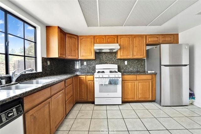 1029 S Reservoir St, Pomona, CA 91766 - kitchen with white appliances, under cabinet range hood, dark stone counters, and brown cabinetry