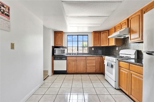 1029 S Reservoir St, Pomona, CA 91766 - kitchen featuring under cabinet range hood, stainless steel appliances, decorative backsplash, dark countertops, and light tile patterned flooring