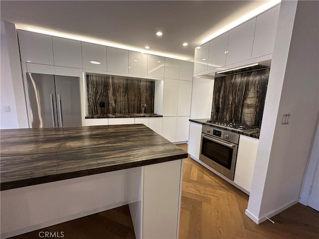 330 N Jackson St Unit 313, Glendale, CA 91206 - kitchen with appliances with stainless steel finishes, butcher block counters, modern cabinets, white cabinetry, and custom range hood