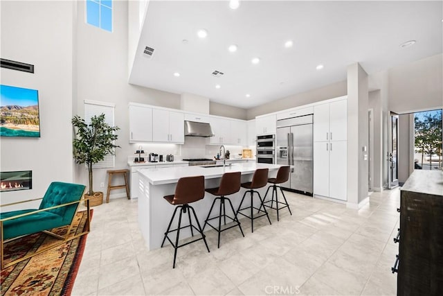 151 Fremont, Lake Forest, CA 92630 - kitchen with stainless steel appliances, under cabinet range hood, a breakfast bar area, light countertops, and a kitchen island with sink