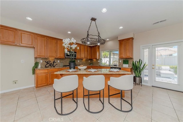 2142 Root St, Fullerton, CA 92833 - kitchen with stainless steel appliances, brown cabinetry, tasteful backsplash, a center island, and light stone counters