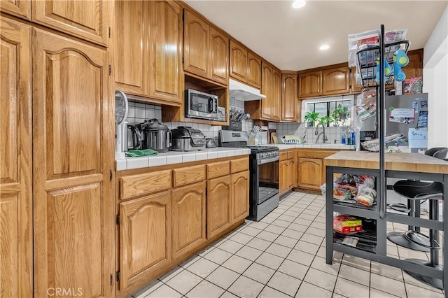 7708 Birchleaf Ave, Pico Rivera, CA 90660 - kitchen featuring appliances with stainless steel finishes, light tile patterned floors, decorative backsplash, tile countertops, and recessed lighting